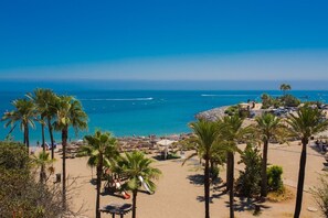 Una playa con palmeras, sombrillas y una vista despejada del océano.