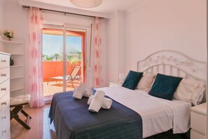 Habitación de hotel con cama, mesita de noche, una silla y vistas al exterior.