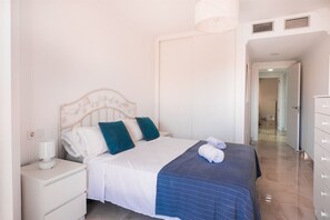 Een hotelkamer met een bed, nachtkastje, lamp en een kledingkast.