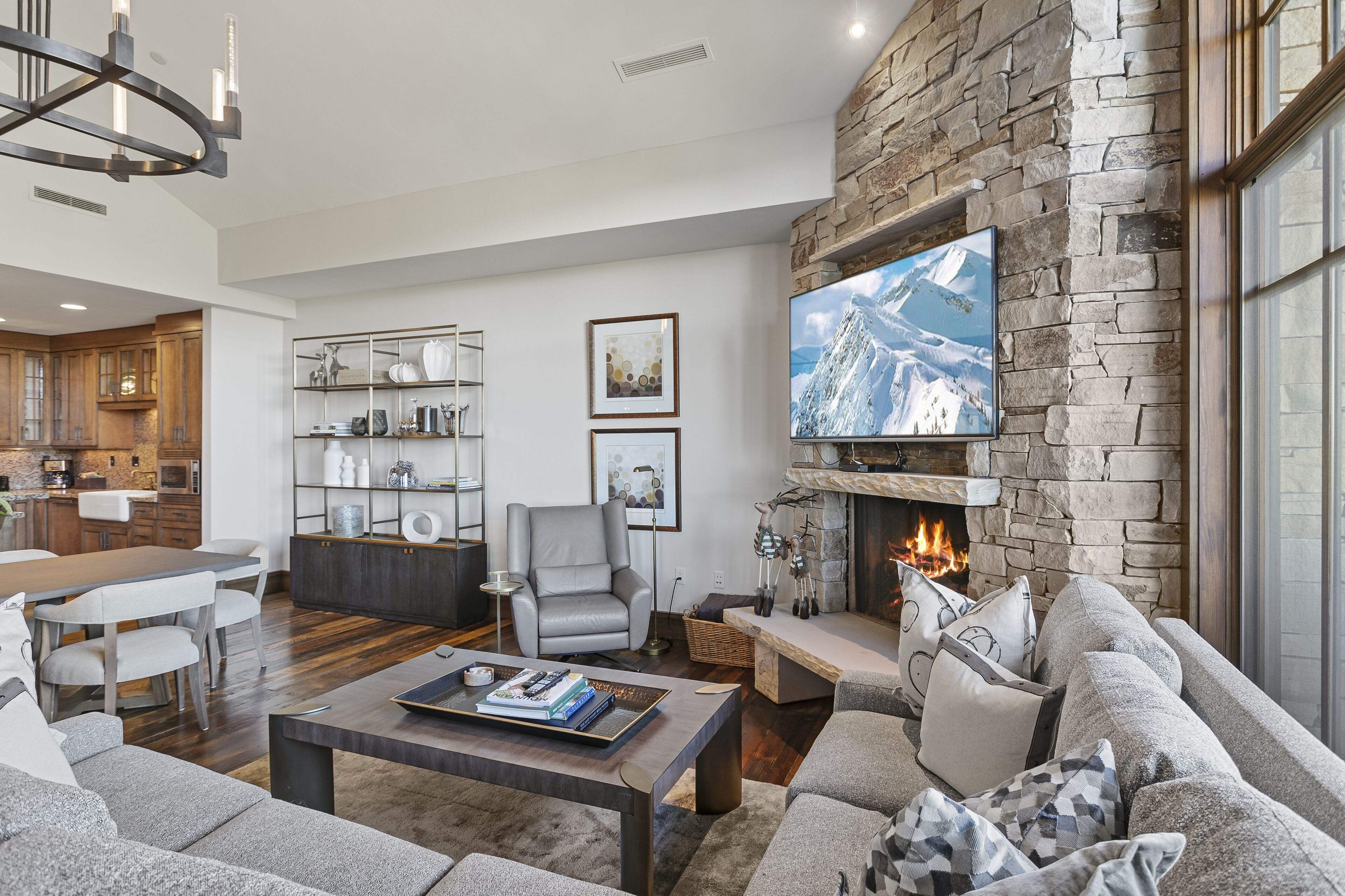 A modern living room with a stone fireplace, a flat-screen TV, and a comfortable seating area.