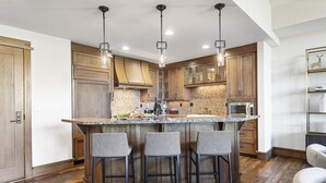 A modern kitchen with wooden cabinets, a central island with bar stools, and pendant lighting.