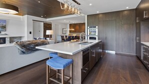 Une cuisine moderne dotée d’un grand îlot central, d’appareils électroménagers en acier inoxydable et de meubles de rangement en bois.