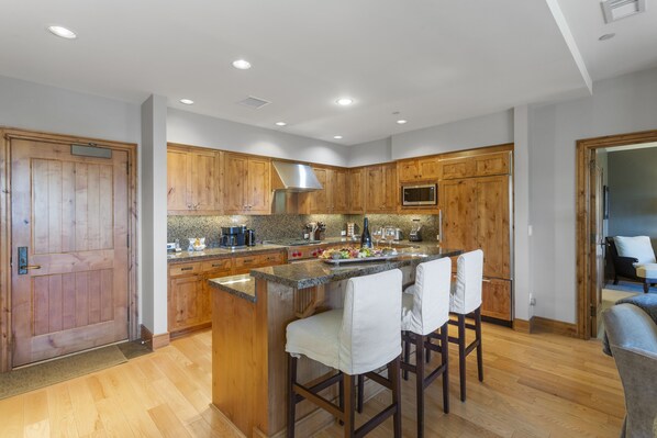 A modern kitchen with wooden cabinets, granite countertops, and a central island with bar stools.