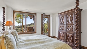 A bedroom with a large bed, a wooden wardrobe, and a window with a view of trees and hills. - Shooting Star Lodge at Deer Valley Resort - Two Bedroom Residence #203 2 Condo (Park City)
