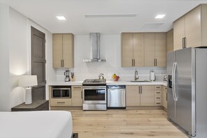 Eine moderne Küche mit Edelstahlgeräten, Holzschränken und einer weißen Küchenrückwand.