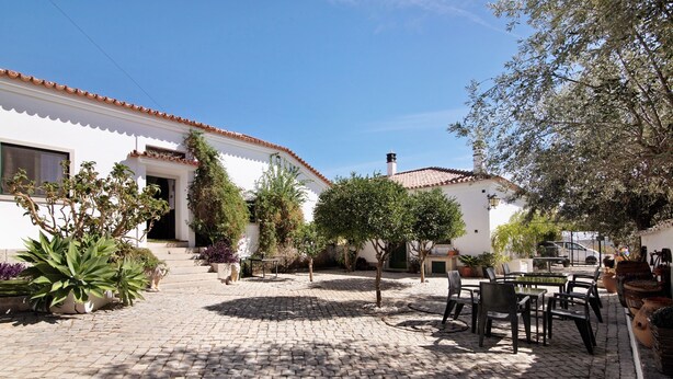 A courtyard with cobblestone paving, outdoor seating, and potted plants. - Private Refuge in a Quiet Area with Shared Pool (São Brás de Alportel)