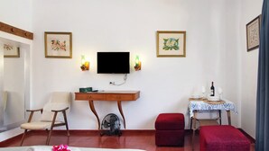 A room with a bed, a desk, a chair, a TV, and a small table with a bottle. - Private Refuge in a Quiet Area with Shared Pool (São Brás de Alportel)