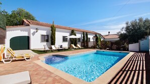 A swimming pool with lounge chairs, a white building with a tiled roof, and a green door. - Private Refuge in a Quiet Area with Shared Pool (São Brás de Alportel)
