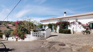 A white building with a tiled roof, a cobblestone driveway, and pink bougainvillea vines. - Private Refuge in a Quiet Area with Shared Pool (São Brás de Alportel)