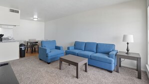 A modern living room with a blue sofa, a coffee table, and a lamp on a side table. - Apt. In college station TX. Mins to major hospitals and A&M U (College Station)