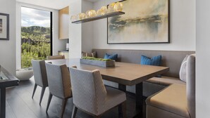 A modern dining area with a large table, cushioned chairs, and a hanging light fixture. - One Empire Pass at Deer Valley Resort - Three Bedroom Residence #402 3 Condo (Park City)