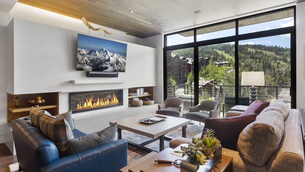 A modern living room with a fireplace, comfortable seating, and a large window offering a mountain view. - One Empire Pass at Deer Valley Resort - Three Bedroom Residence #402 3 Condo (Park City)