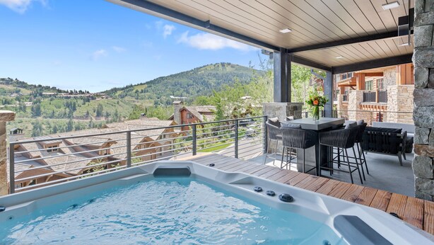 Un bain à remous sur une terrasse en bois, avec vue sur un paysage montagneux.