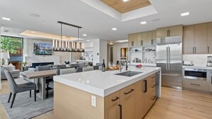 Une cuisine moderne dotée d’un îlot central, d’appareils électroménagers en acier inoxydable et de meubles en bois.