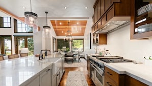 A modern kitchen with a central island, wooden cabinets, and pendant lighting.