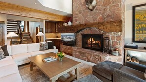 A spacious living area with a stone fireplace, a mounted deer head, and a cozy seating arrangement.