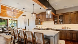 A modern kitchen with wooden cabinets, a large island, and pendant lighting.