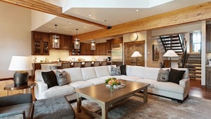 A spacious living area with a large sectional sofa, a wooden coffee table, and a kitchen in the background.