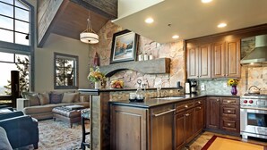 A spacious kitchen with stone walls, wooden cabinets, and a large island. - Stag Lodge at Deer Valley Resort - Three Bedroom Residence with Spa #13 3 Condo (Park City)