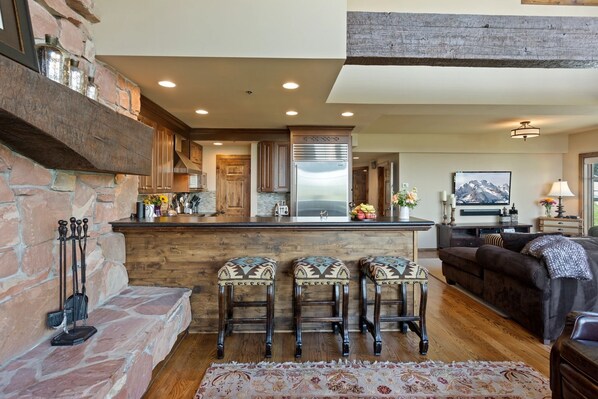 A modern kitchen with a stone accent wall, wooden bar stools, and a central island.