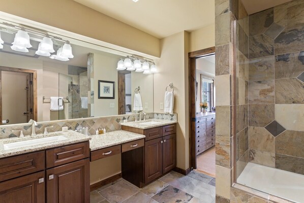 Une salle de bain moderne avec deux lavabos, un grand miroir et un espace douche.