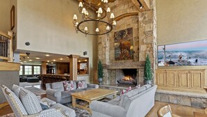 A spacious living area with a stone fireplace, comfortable seating, and a large television screen.