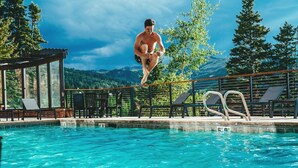 A man diving into a pool with a mountain view.