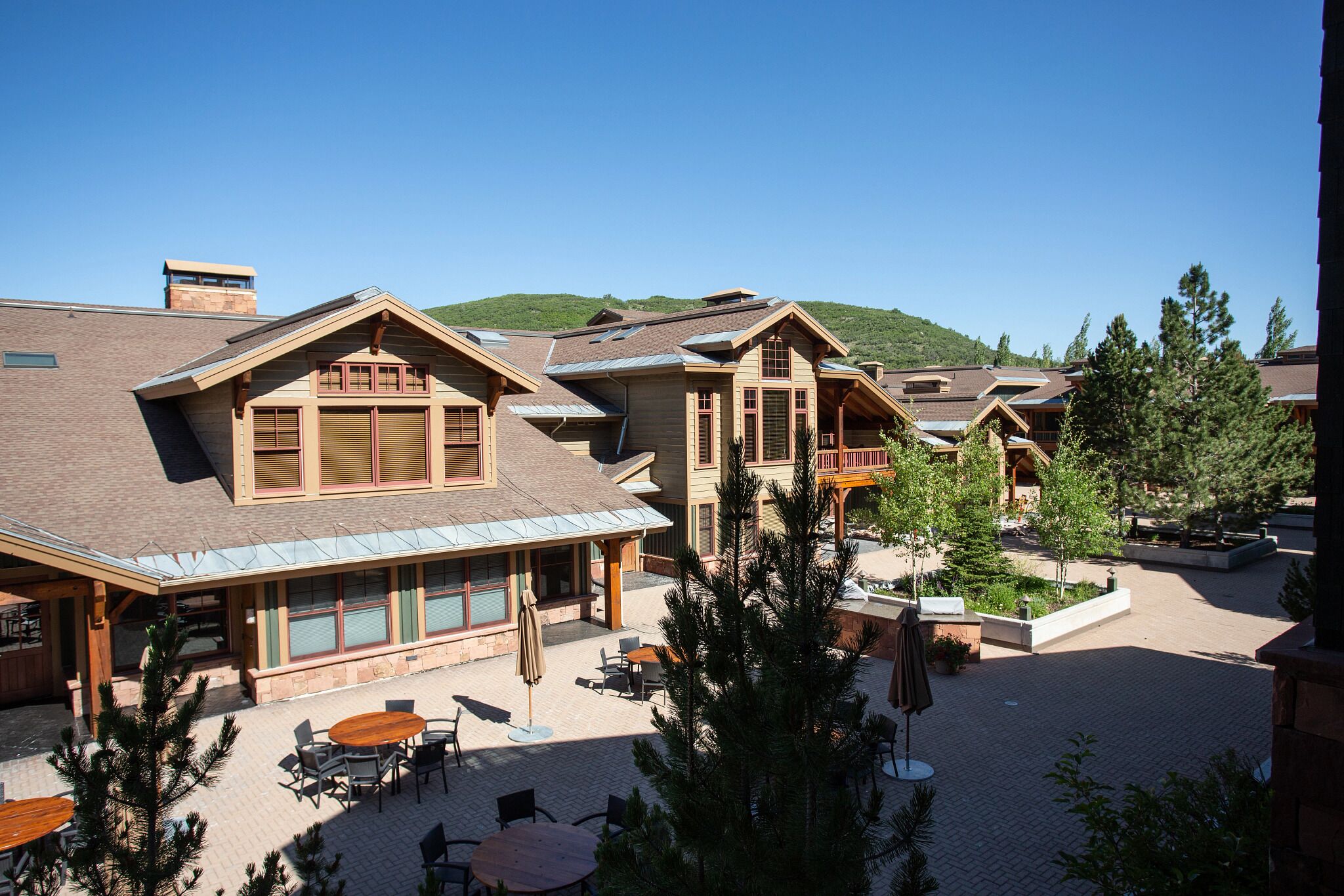 A resort with multiple buildings, outdoor seating areas, and a mountainous backdrop.