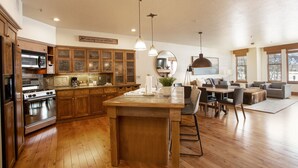 A spacious kitchen with wooden cabinets, a large island, and a dining area with a sofa and chairs. - The Lodges at Deer Valley 1 Bedroom Condo (Park City)