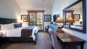 A hotel room with a bed, desk, chair, lamp, television, and large mirror. - The Lodges at Deer Valley Hotel Room (Park City)