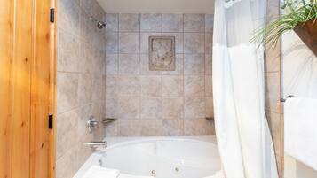 A bathroom with a bathtub, wooden door, tiled walls, and a shower curtain.