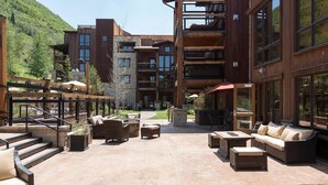 A courtyard with outdoor seating, a stone fireplace, and a view of a mountain.
