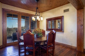 A dining area with a wooden table and chairs, a chandelier, and a large mirror on the wall. - Grand Lodge - 3 Bedroom Condo Deluxe #308 - Ski-in/out by Deer Valley Resort (Park City)