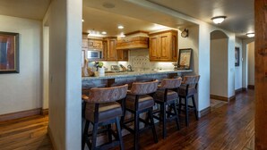 A kitchen with wooden cabinets, a microwave, and a clock on the wall.