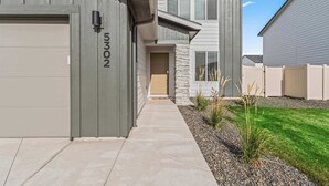 A modern two-story house with a garage, a stone accent wall, and a well-maintained lawn.