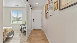 A hallway with a bed, a desk, and a door.