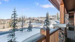A wooden balcony with a stone ledge overlooking a snowy landscape with buildings and trees. - Grand Lodge - 3 Bedroom Condo Deluxe #206 - Ski-in/out by Deer Valley Resort (Park City)