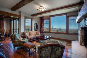 Amplia sala de estar con ventanas grandes, vigas de madera y chimenea.