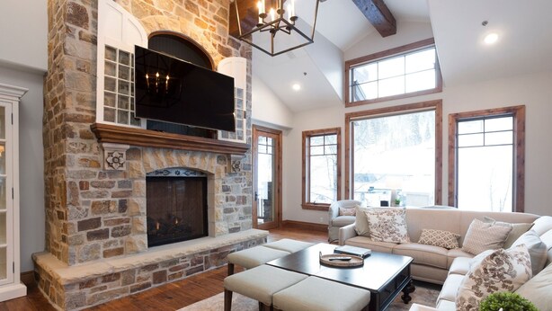 A spacious living room with a stone fireplace, a large window, and a comfortable seating area. - Grand Lodge - Five Bedroom Condo #402 - Ski-in/ski-out by Deer Valley Resort (Park City)