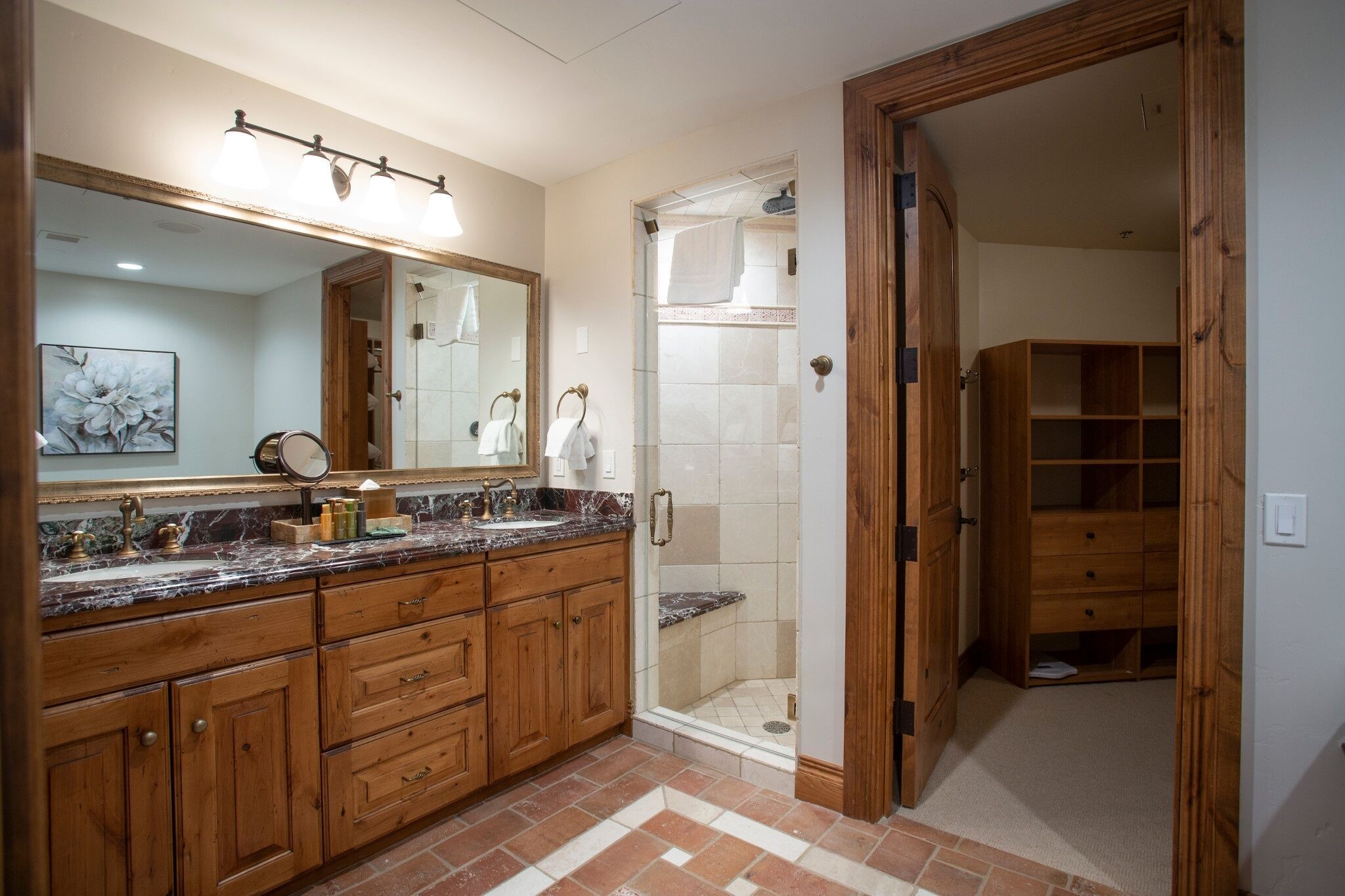 Un baño con armarios de madera, un espejo grande, cabina de ducha y vestidor.
