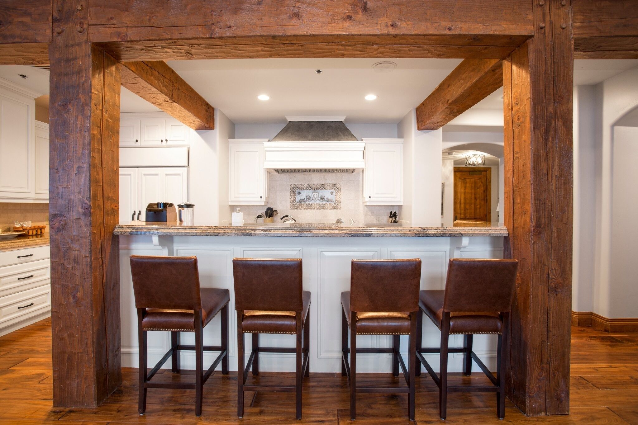 A kitchen with a central island, white cabinets, and a wooden ceiling structure.