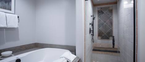 A modern bathroom with a bathtub, shower, and tiled floor.