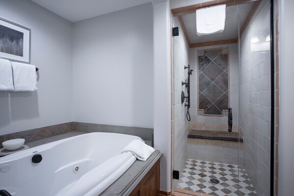 A modern bathroom with a bathtub, shower, and tiled floor.