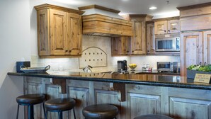 A kitchen with wooden cabinets, a central island with stools, a microwave, and a sign indicating it is a non-smoking area.