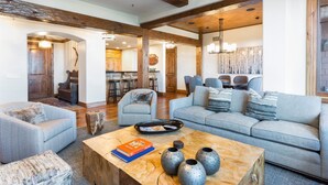 A spacious living area with a large sofa, a coffee table with books and vases, and a wooden accent wall.