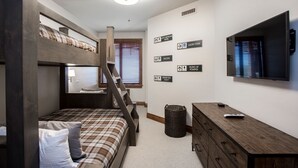 A bedroom with a bunk bed, a desk, a TV, and motivational wall art.