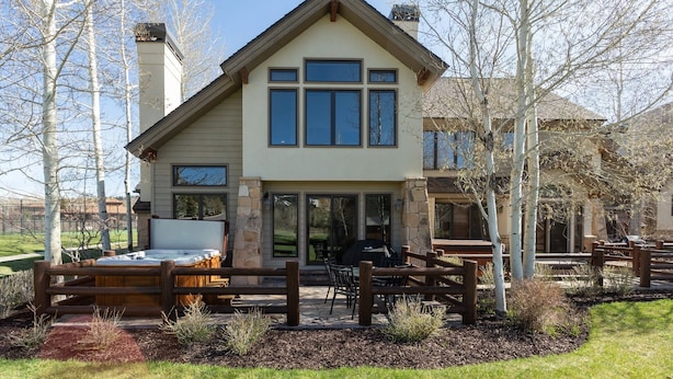 A two-story house with a stone facade, large windows, and a patio area with outdoor seating. - Deer Lake Village at Deer Valley Resort - Four Bedroom Condo with Hot Tub #2477 4 Condo (Park City)