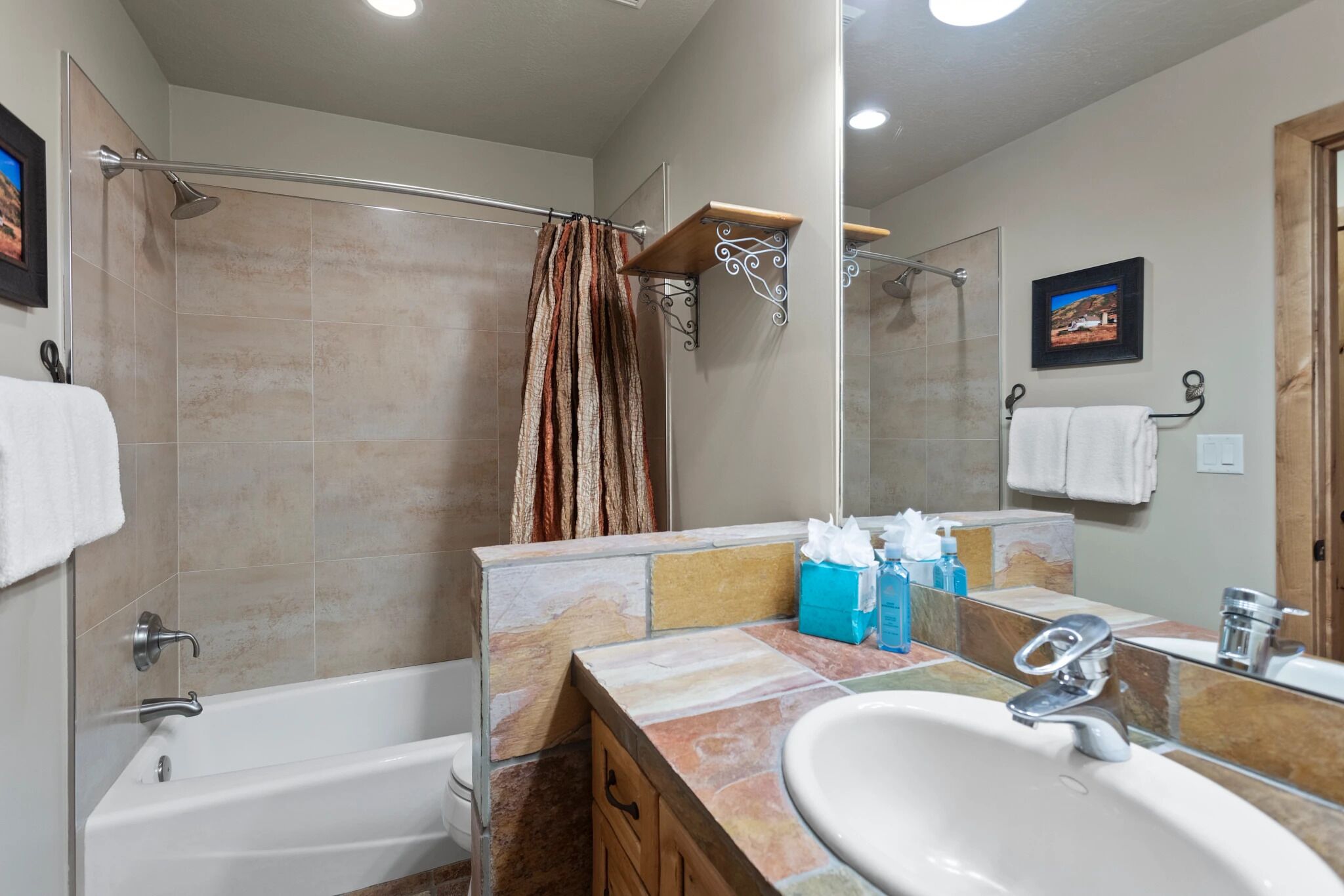 A bathroom with a bathtub, shower, vanity with a sink, and a mirror.