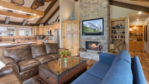 A spacious living room with a stone fireplace, leather sofas, and a flat-screen TV mounted on the wall. - Queen Esther at Deer Valley Resort - Two Bedroom Condo with Hot Tub #2346 2 Condo (Park City)