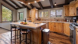 A spacious kitchen with wooden cabinets, a large island with stools, and a stainless steel stove. - Queen Esther at Deer Valley Resort - Two Bedroom Condo with Hot Tub #2346 2 Condo (Park City)